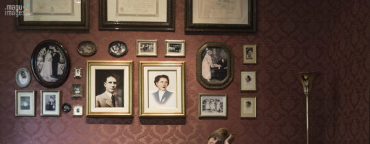 Una mujer sola en un salón antiguo. El cuerpo en movimiento, casi suspendido, como si escuchara una música que no se oye. Detrás, una pared cubierta de retratos: miradas del pasado que observan, acompañan, sostienen.