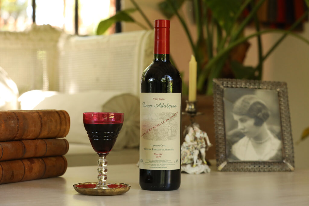 Botella de vino Finca Adalgisa servida en copa, en un ambiente íntimo dentro de la finca.