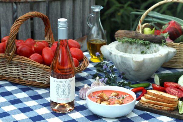 Fresh gazpacho served with rosé wine on a rustic table, surrounded by seasonal ingredients like tomatoes, garlic, and vegetables from Mendoza. Rosado de Familia Furlotti maridaje gazpacho Mendoza